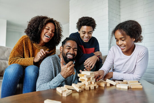 Portrait of a happy african american family at home, having fun playing wooden brick challenge game, playing board game jenga at home