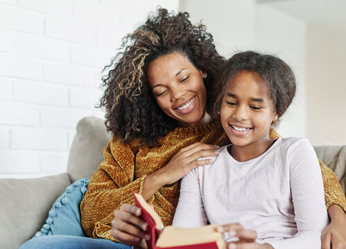 Mother and daughter reading a book on sofa at home