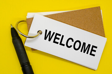 Open notebook with WELCOME sign on the front, upright pen beside it