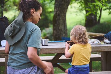 Mother and Child Enjoying Outdoor Moments at a Picnic Table in Nature