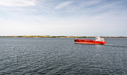 A chemical oil tanker sails through the Øresund Strait, transporting goods between Denmark and Sweden. Calm waters and distant land create a serene backdrop