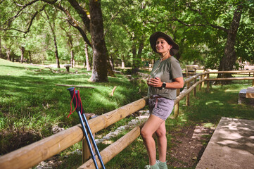 Woman Enjoying a Refreshing Drink in a Green Park While Hiking