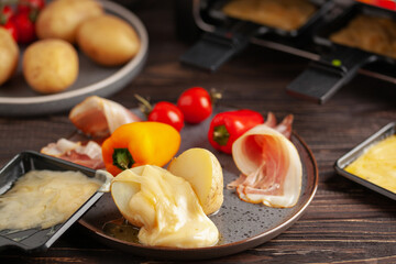 Delicious traditional Swiss melted raclette cheese on diced boiled or baked vegetables served in...