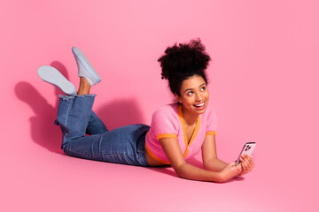 Young woman with phone on pink background smiling, representing trendy, casual, and fresh modern...