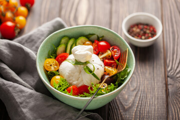 Salad with traditional italian burrata cheese. Burrata ball with cherry tomatoes, cucumber slices,...