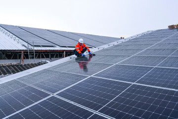 Engineers install solar panels on a wet rooftop during cloudy weather