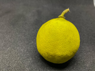 yellow citrus lemon fruit black dark textured surface.