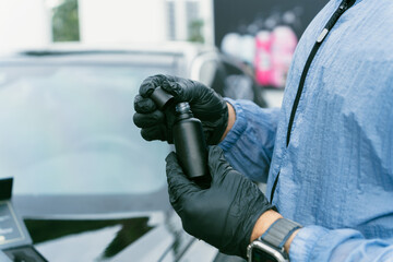 A person wearing black gloves and a blue protective suit is shown precisely handling a small black...