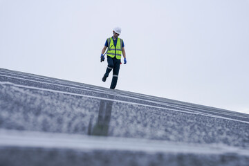 Engineers install solar panels on a wet rooftop during cloudy weather