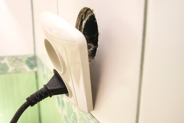 Broken electric socket in a house or apartment, showing the danger of an exposed power outlet that needs repair. A hazardous broken plug socket in a bathroom or house