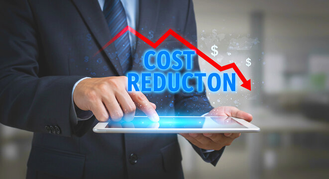 Man in suit using tablet with cost reduction graphic and downward arrow overlaying the screen image