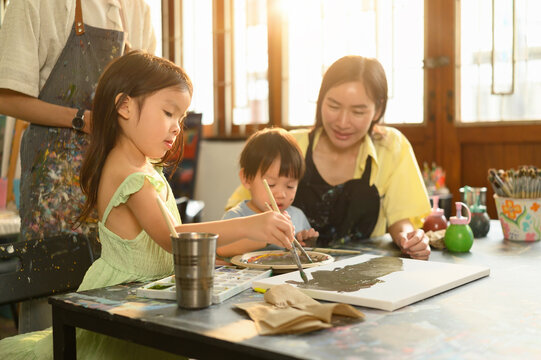 Young kids use paintbrushes to work on a shared art project, fostering creativity and motor skills development, Kindergarten Art Class Concept