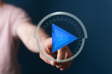 Hand presses a digital play button.  Concept for media, technology, innovation.