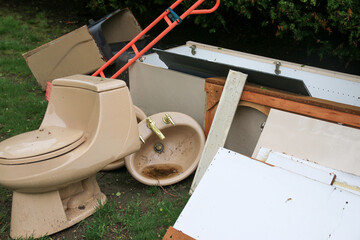 Discarded Bathroom Fixtures and Debris Piled on Grass during renovation