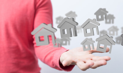 Image of a person's hand holding multiple digital house icons, symbolizing real estate, property,...