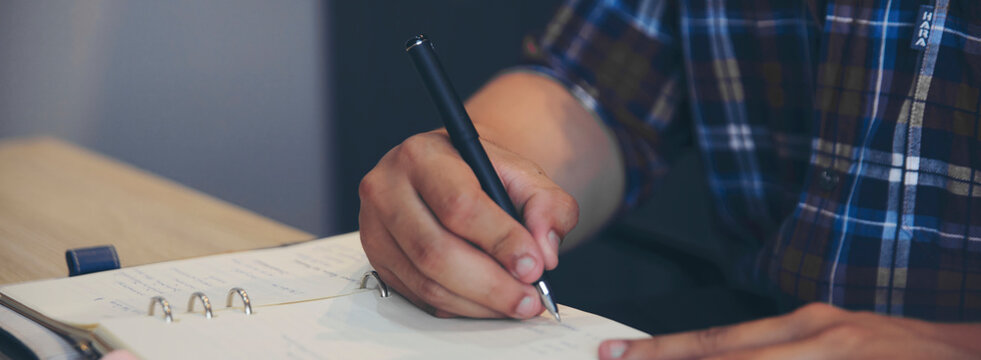 Planner or organizer writing daily appointment in Calendar book. Asian woman hand plan timetable meeting agenda, and notes schedule of business in diary. Planner concept-banner image.