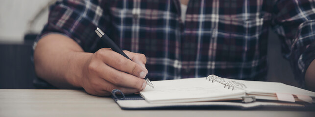 Planner or organizer writing daily appointment in Calendar book. Asian woman hand plan timetable meeting agenda, and notes schedule of business in diary. Planner concept-banner image.