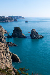 seascape with cliff, rocks and fishing boat