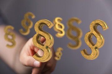 Abstract image of a hand selecting golden paragraph symbols. Perfect for legal, law, and justice concepts.