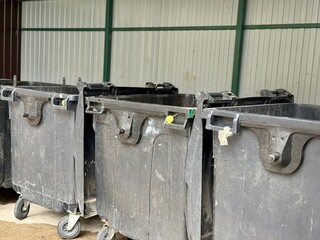 A Row of Industrial Waste Bins Equipped with Wheels for Easy Transportation and Use. A set of...