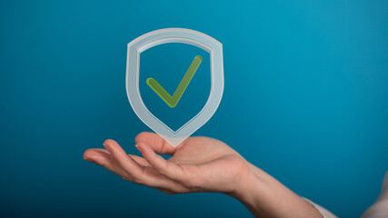 Image of a hand holding a digital shield with a checkmark, symbolizing security, safety, and...