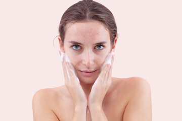 Close up of a young woman washing her face with hands covered in foam touching her skin. Deep...