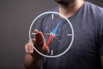 A man uses a finger to interact with a digital compass interface.  Concept of direction, guidance,...