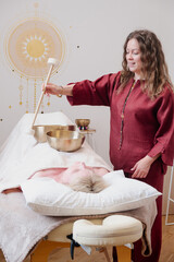 Wellness practitioner conducting sound therapy using Tibetan singing bowls placed on a person...