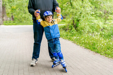 Father teaching son roller skating in park.Sport,communication between parents children,parenting...