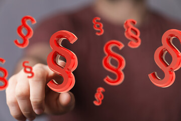Abstract image of a hand interacting with floating 3D paragraph symbols, ideal for legal or...