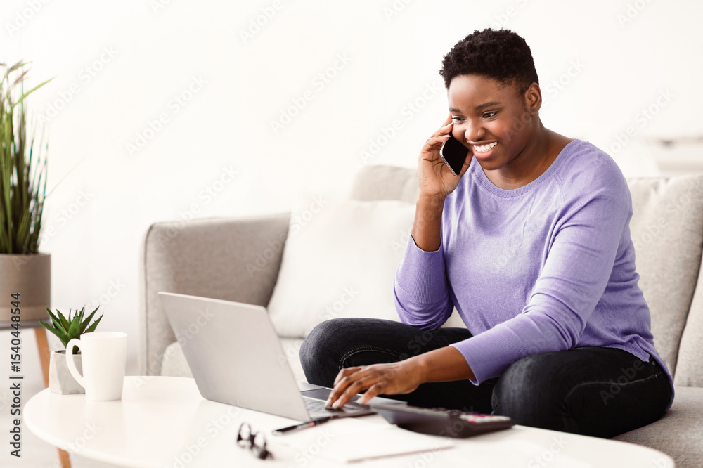 Poster multitasking at home. smiling young plus size black lady making call using her smartphone, sitting o