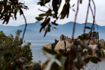small island with historical ruins at Bafa Lake, dry tree, volcanic rock formation on waterfront