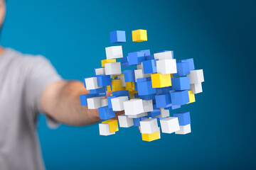 Abstract image of a hand reaching towards a dynamic cluster of blue, white, and yellow cubes,...
