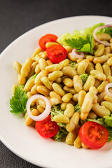 Bean salad green leaf lettuce, tomato, onion vegetables dish fresh delicious gourmet food background on the table rustic food top view copy space keto and paleo diet vegan and vegetarian food