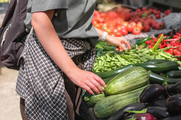 Young woman choosing fresh organic vegetables at a local market. Concept of eco lifestyle,...
