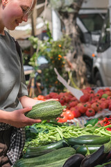 Young woman choosing fresh organic vegetables at a local market. Concept of eco lifestyle,...