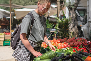 Young woman choosing fresh organic vegetables at a local market. Concept of eco lifestyle,...