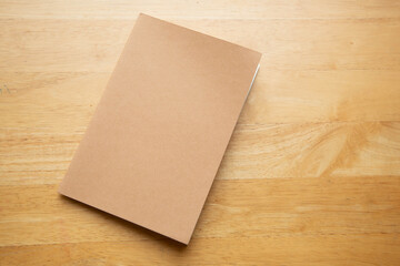 Top view of blank brown closed book on wooden table 