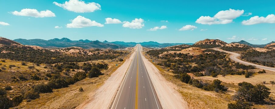 Construction infrastructure highway progress concept. A vast highway stretches into a scenic desert landscape under a blue sky.