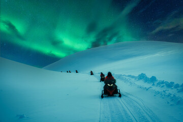 Snowmobile adventure across snowy mountain track with aurora borealis in winter