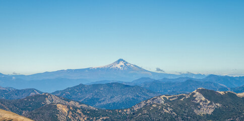 Prominent snowcapped Villarrica volcano rises above layers of hazy mountain ranges. Patagonia,...