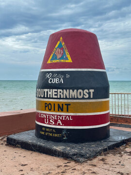 Colorful, iconic Southernmost Point Buoy in Key West, Florida, marking the southernmost point of the continental United States. Painted with bold stripes and reading "90 Miles to Cuba"
