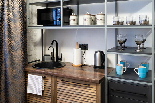 Compact kitchenette with microwave, sink, kettle, and rustic wooden decor in cozy studio