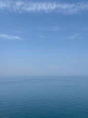 Blue sea blue sky fluffy clouds horizon.