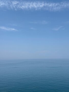 Blue sea blue sky fluffy clouds horizon.