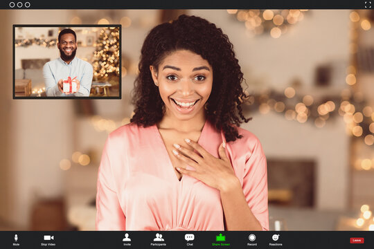 Celebration During Quarantine. Happy amazed black woman having online video call with her man, guy showing present gift box to his girlfriend at videochat. Screen view with conference app