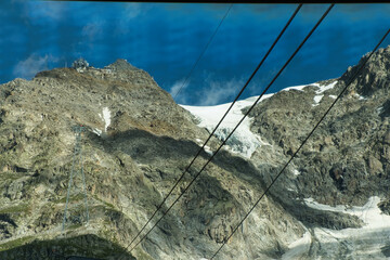 man takes a photo of the sky way cable car at punta hellbronner on mont blanc among the snowy mountains in august