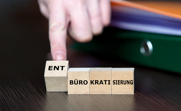 Hand dreht W&uuml;rfel und &auml;ndert den Ausdruck 'B&uuml;rokratisierung' in 'Entb&uuml;rokratisierung'.