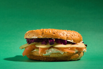 Gourmet bagel sandwich featuring smoked salmon, cream cheese, red cabbage, and apple slices,...