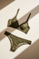 Olive green bra and underwear set on neutral surface, natural sunlight and soft shadows, minimalist, modern, stylish display.